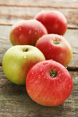 Ripe and sweet apples with water drops on wooden table