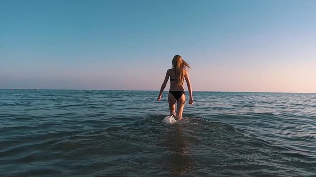 The girl comes into the ocean.