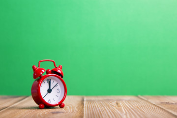 red alarm clock on a green background
