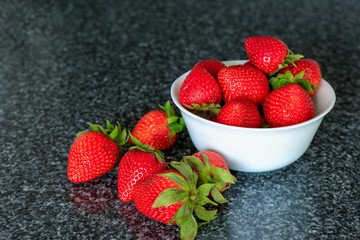 Small white bowl filled with red strawberries.