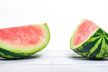 Two pieces of a watermelon on white wooden table on white background background front view. Blank minimalistic background