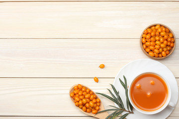 Sea buckthorn in wooden bowl, Sea buckthorn juice on wooden table. top view with copy space