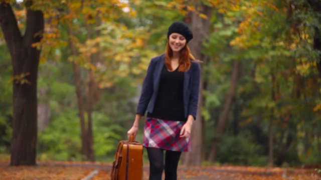 Video of Young woman with suitcase at autumn park outdoor 