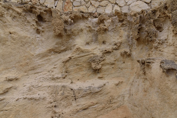 Front view of the natural background of yellow limestone with the bumpy surface with dark hollows that are smoothed by the sea waves 02