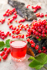 Boiling red currant drink in a glass and berries on a tree bark