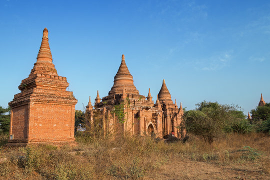 View of old and untitled pagodas and brick buildings in Bagan, Myanmar (Burma) on a sunny day.