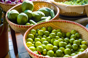 lime, coconut and cucumber in big baskets on light market