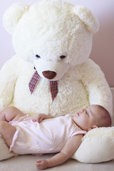 Bebé durmiendo sobre el regazo de un oso de peluche - 169746604