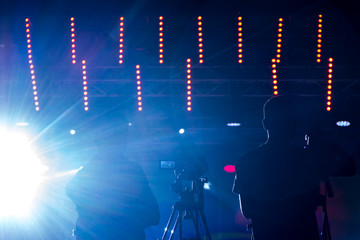 two videographers on the shooting of the concert against the bright backlight.