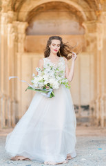 Fototapeta na wymiar Romantic beautiful bride in luxury dress posing of beautiful architecture