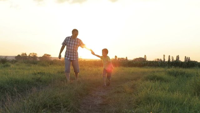 Father and son playing  at the sunset time. People having fun outdoors. Concept of friendly family.