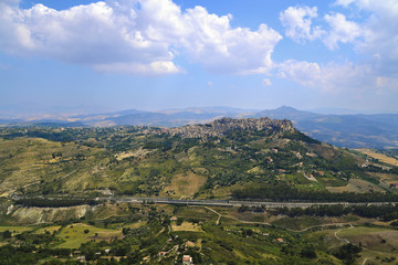 Fototapeta premium View of Calascibetta Mediterranean city on the hill from Enna Town. Classic old Italy, Sicily. Scenic Village On The Side Of A Rock.