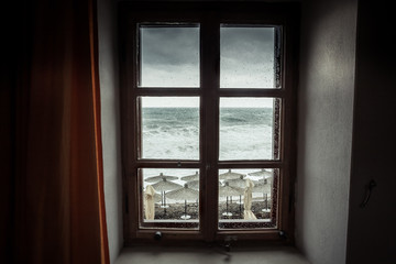 Fenêtre vintage avec vue spectaculaire sur la mer avec de grosses vagues orageuses et un ciel couvert dramatique pendant la pluie et les tempêtes en automne sur la côte de la mer