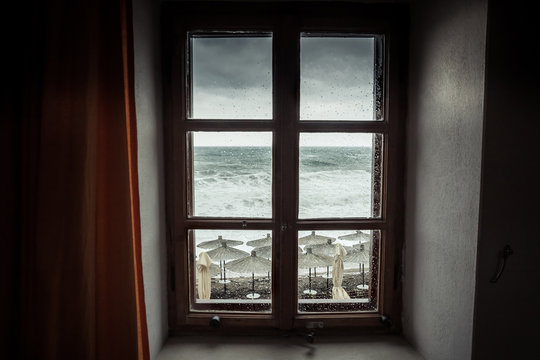 Vintage window with dramatic sea view with big stormy waves and dramatic overcast sky during rain and storm weather in fall season on sea coast