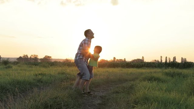 Father and son playing  at the sunset time. People having fun outdoors. Concept of friendly family.