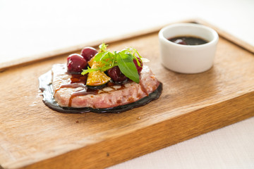 roast tuna piece on wooden plate with chopsticks isolated over white background