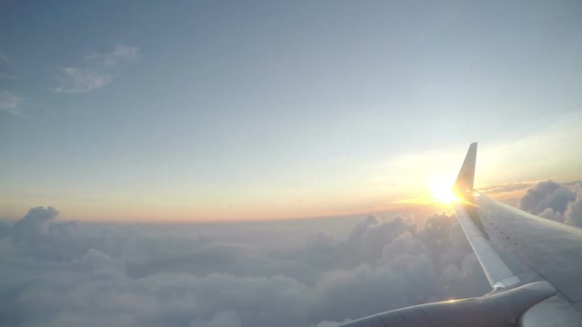 View from the plane flying over clouds on rising of the sun