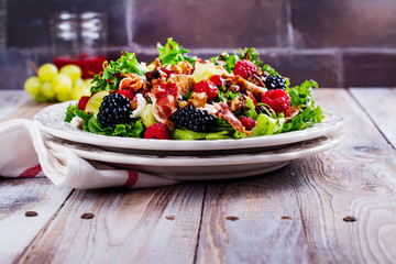 Delicious summer salad with mix of berries, nuts, feta chees, bacon and raspberry sauce on vintage background. Space for text