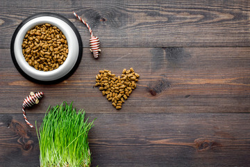 bowl full and overflowing with dry pet - cat food bits and mouse toys on wooden background top view mock-up