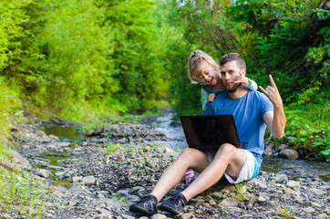 Family watching a movie on a laptop sitting in a park, free space.