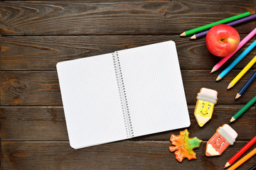 Naklejka na ściany i meble Back to school concept. Open notebook and apple with colored pencils, gingerbread on wooden background