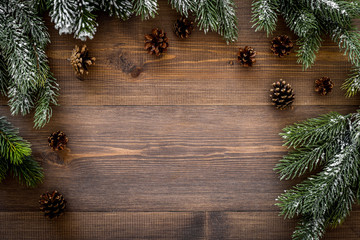 New year frame. Spruce branch and pine cones on dark wooden background top view copyspace