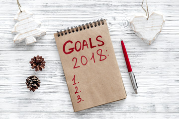 Make a goals list for 2018. Notebook near pen on grey wooden background top view   