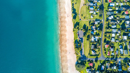 Aerial view on small suburb on a sunny ocean beach. Coromandel peninsula, New Zealand