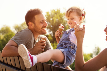 Happy young family eating ice cream and having fun outside