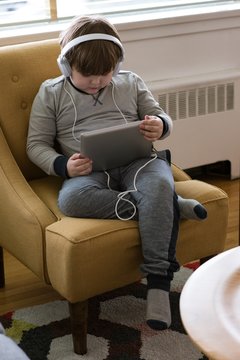 High angle view of boy wearing headphones while using tablet