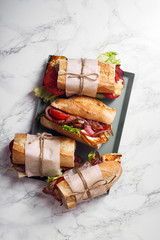 Fresh baguette sandwich bahn-mi styled. Bacon, roasted cheese, tomatoes and lettuce on metallic...