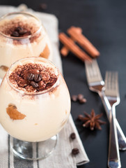 tiramisu in a glass decorated with coffee beans on a dark background