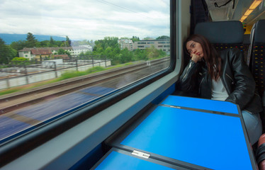 Asian woman looks outside of the train's window, looking bored or tired of traveling too long.