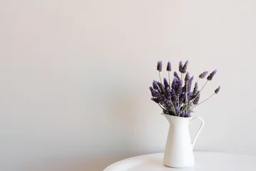 Photo sur Plexiglas Lavande Purple lavender in small white jug on edge of round table against neutral wall with copy space to left