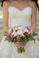 bride with beautiful wedding bouquet of roses, peonies and other flowers