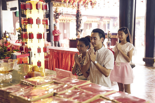 Blissful family praying quietly in a Temple in Telok Ayer, Singapore