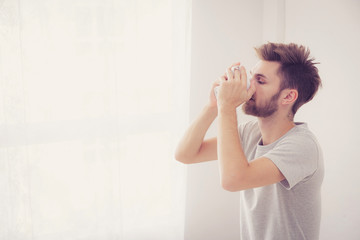 american man with cup of coffee in bedroom with morning.