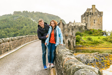 Couple visiting Eilean Donan castle in Highlands mountains in Scotland