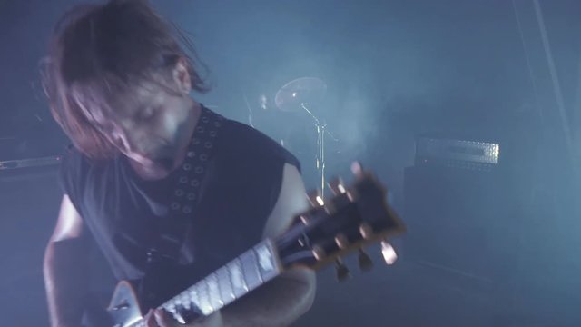 Concert rock band performing on stage with Frontman, guitarists and drummer. Music video punk, heavy metal or rock group.