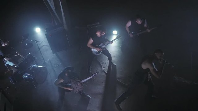 Concert rock band performing on stage with Frontman, guitarists and drummer. Music video punk, heavy metal or rock group.