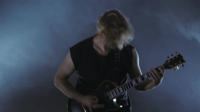Brutal male rocker plays the electric guitar. Music video punk, heavy metal or rock group.