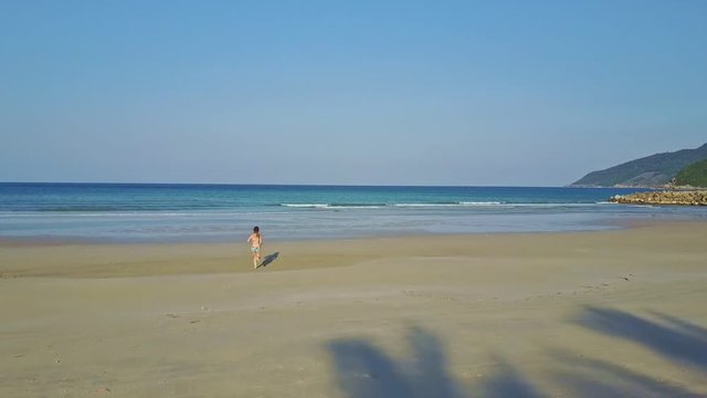 Backside View Flycam Shows Girl Running along Ocean Beach
