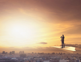 Fototapeta premium business man on paper plane spying by binocular to urban scene