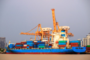 Fototapeta premium Shipping trade port. Container cargo ship loading or unloading by crane bridge. Logistics industrial and transportation business background