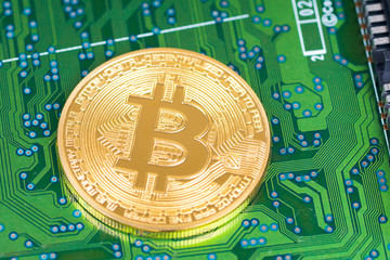 bitcoin metallic coin on green electronic board closeup shot