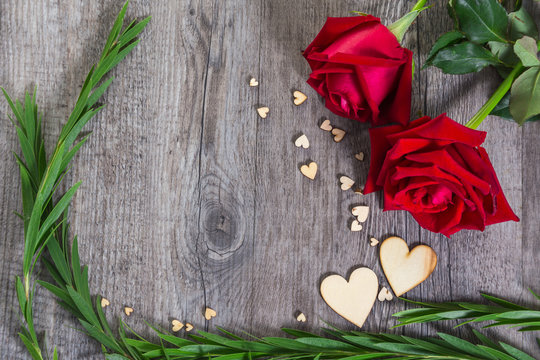 Heart shape with green foliage and red rose flower on wood texture background, Studio shot on wooden background.