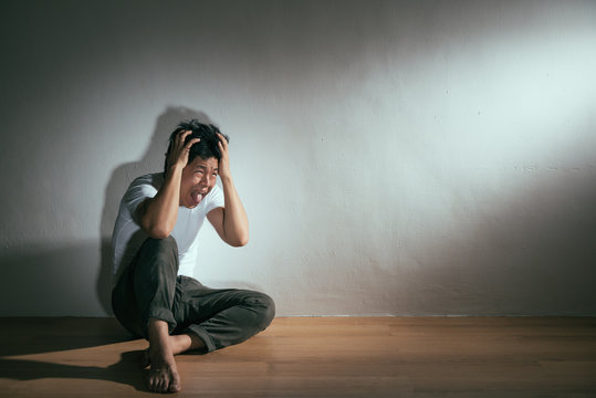 Collapsed Man Sitting On Wood Floor Hand Hold Head