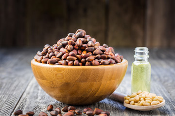 Pine nuts oil, peeled and whole pine nuts on wooden background. Selective focus, copy space.