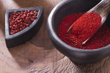Achiote grains and powder in wooden bowl