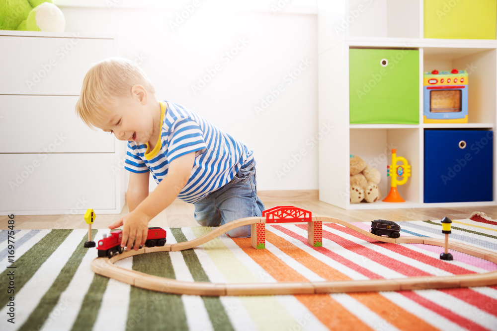 Wall mural little child playing with railroad